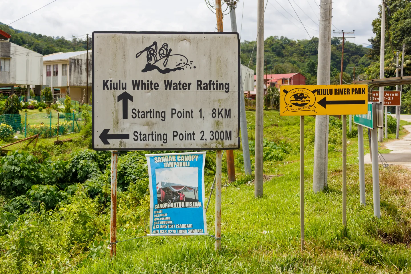 Roadside direction signs for Kiulu white-water rafting near Tamparuli; the photo shows signage, not rafting action.