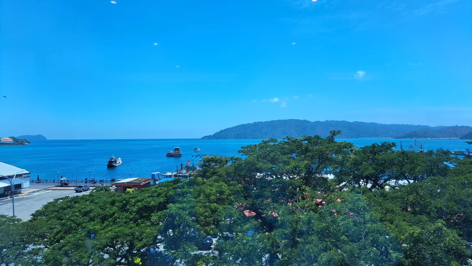 Kota Kinabalu waterfront on a clear day, with boats in the bay and Gaya Island beyond